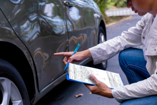 person looking at damaged car