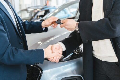 person handing car keys and shaking hands