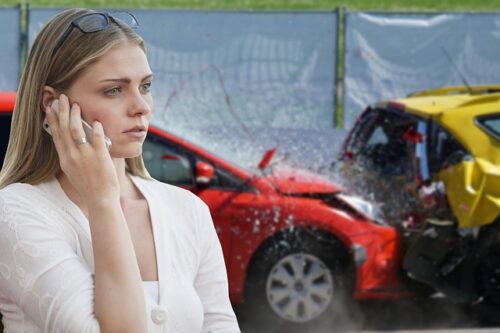 woman on phone in front of car crash
