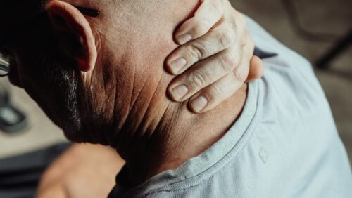 man grabbing back of neck in pain